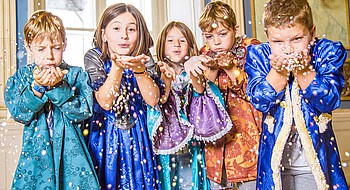 Kinderprogramm im Schloss Esterházy©Esterházy/Andreas Tischler Fünf Kinder in bunten Kostümen pusten Konfetti durch die Luft